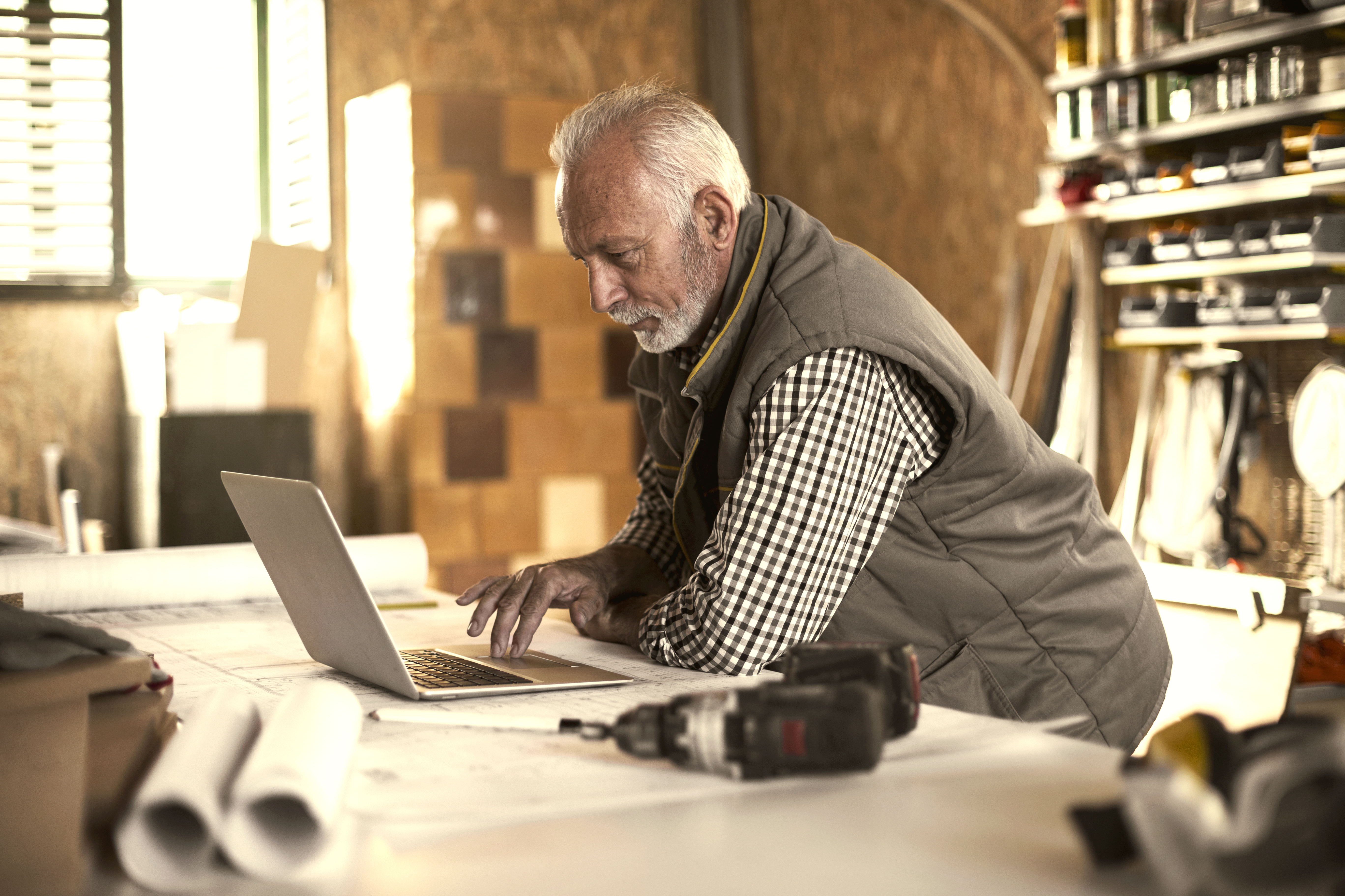 Older man leaning over using trackpad on laptop