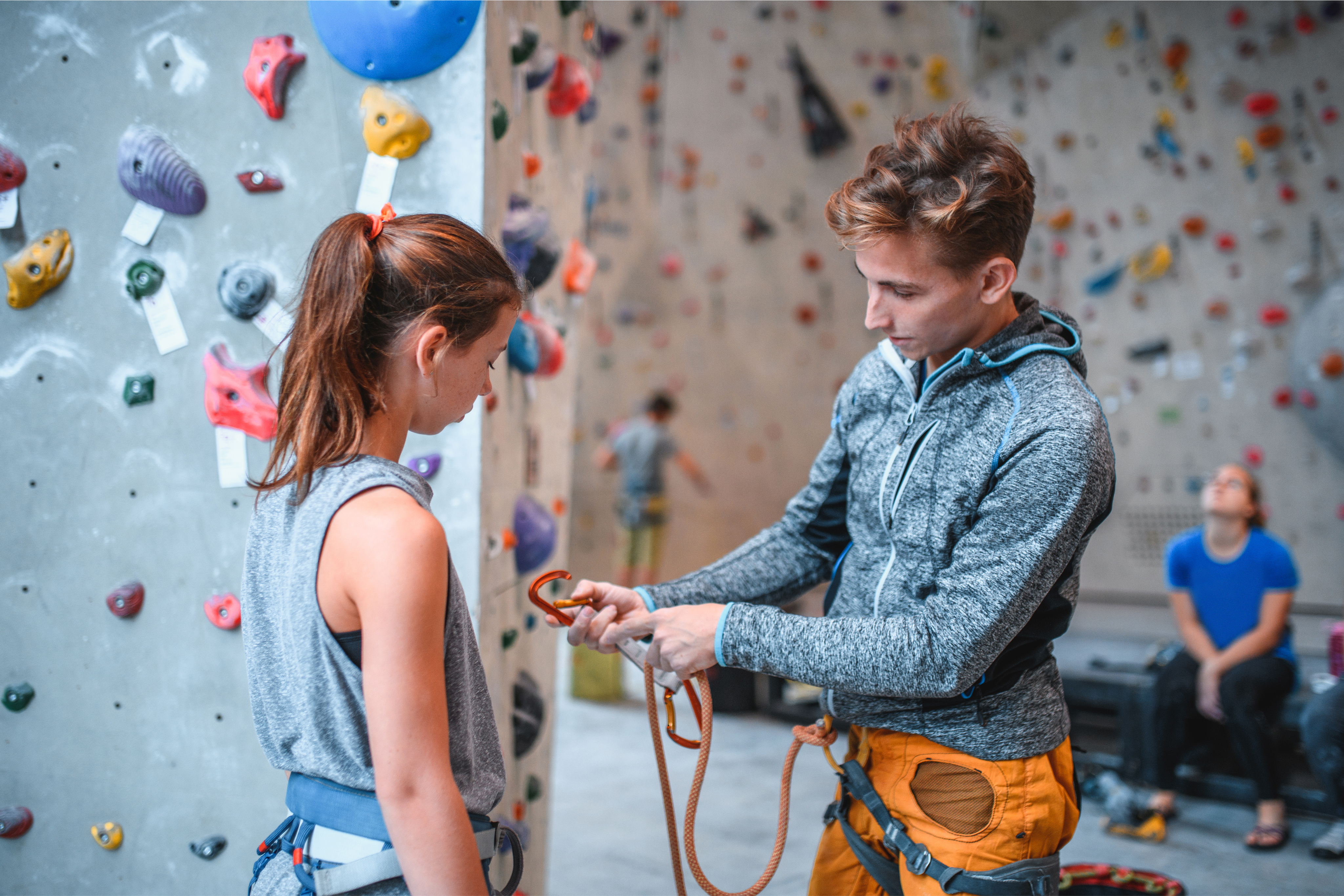 Rock climbing gym employees attaches safety harness