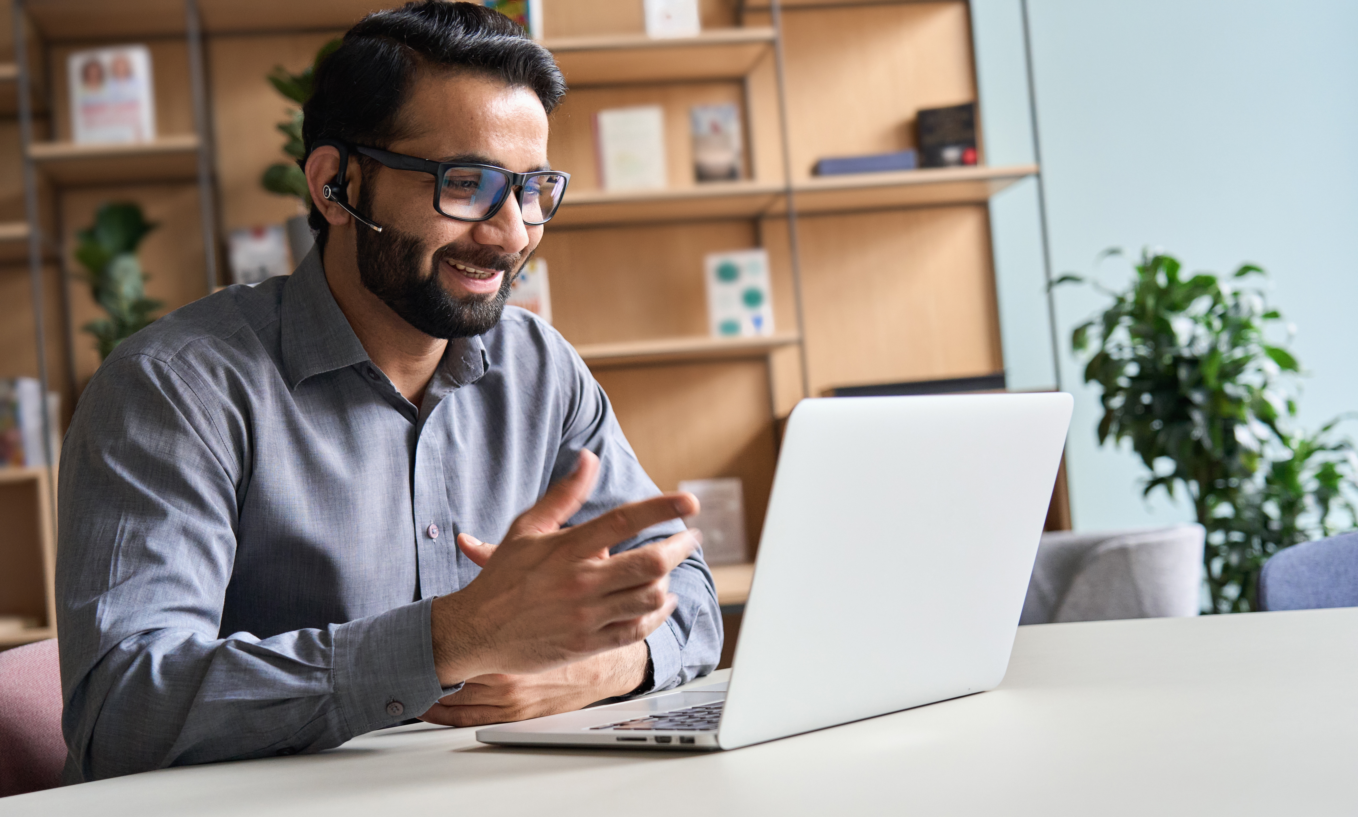 Business man wearing headset talking at virtual meeting consulting client on video call 